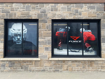 Casque de hockey blanc avec visière noire et accents rouges exposé dans une vitrine.